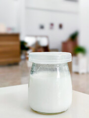 Homemade kefir, buttermilk, or yogurt with probiotics in a bottle on a white table in a cafe. Trendy and healthy food and drink
