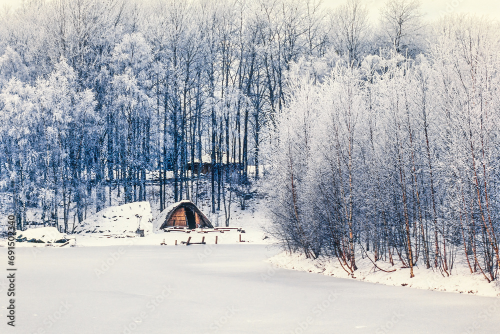 Wall mural Frozen lake with a grass huts on the lakeshore a cold winter day