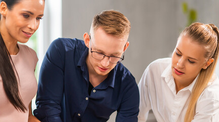 Team of young and confident startupers is working at the table in the office, discussing the strategy and development plan of the company. Business, innovation, brainstorming and teamwork.