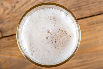 Top view of beer foam in a glass. Wooden background.