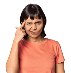 Young Hispanic woman with short black hair in studio pointing temple with finger, thinking, focused on a task.