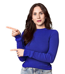 Young Caucasian woman in a studio setting excited pointing with forefingers away.