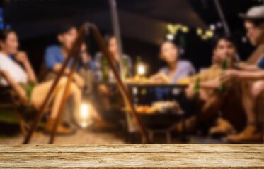 Wooden table top on blur tent camping travel tent at night.Drink and party concept.For montage...