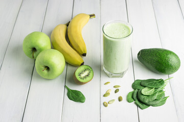 Green detox smoothie, blended vegetarian drink in a glass from spinach, apple, banana, kiwi,...