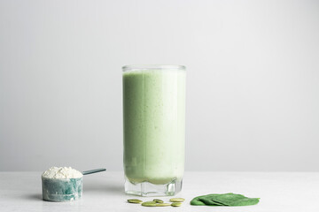 Green detox smoothie, blended vegetarian drink in a glass from protein powder, spinach and seeds on a table, healthy eating concept - obrazy, fototapety, plakaty