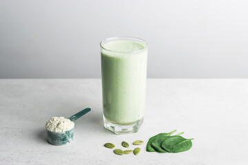 Green detox smoothie, blended vegetarian drink in a glass from protein powder, spinach and seeds on...