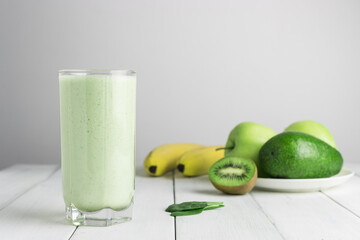 Green detox smoothie, blended vegetarian drink in a glass from spinach, apple, banana, kiwi,...