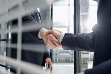 executives shaking hands in front of their manager and a colleague