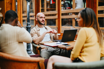 Diverse corporate team brainstorm for a marketing campaign in a trendy urban coffee bar, discussing...