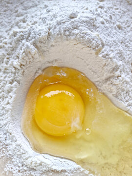Aufgeschlagenes Ei im Mehl. Vorbereitung eines Teiges. 