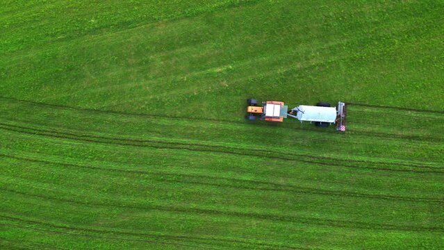 This footage provides a bird's-eye view of a tractor performing fieldwork, leaving behind a pattern of fresh tracks on a lush green canvas. The contrast between the darker soil turned over by the plow