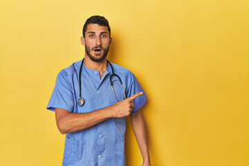 Young Hispanic male nurse Young Hispanic male nurse poses confidently pointing to the side< mixto > - obrazy, fototapety, plakaty