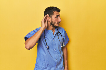 Young Hispanic male nurse Young Hispanic male nurse poses confidently trying to listening a gossip.< mixto >