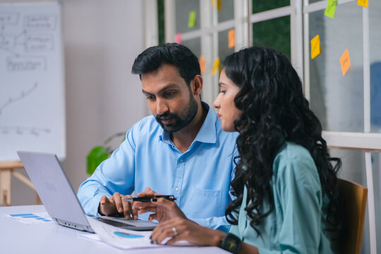 Male and female Coworkers at office discussing from laptop during meeting - concept of expert guidance, startup collaboration and business planning