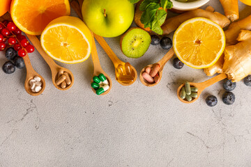 Vitamins and supplements. Variety of vitamin tablets in a wooden spoon on a texture background.Multivitamins with fresh and healthy fruits.Food supplements. Flat lay. Space for text.Copy space