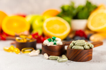 Fototapeta na wymiar Vitamins and supplements. Variety of vitamin tablets in a wooden spoon on a texture background.Multivitamins with fresh and healthy fruits.Food supplements. Flat lay. Space for text.Copy space