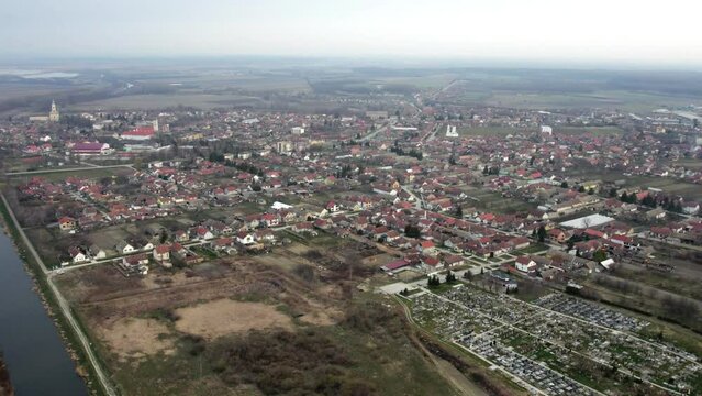 Aerial view of canal, houses and cemetery in small town Bac, Serbia