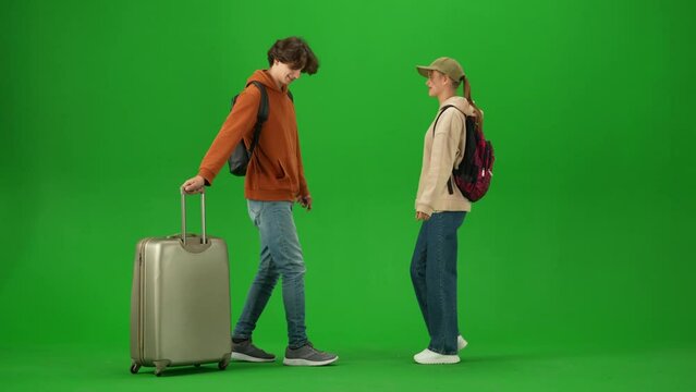 Portrait of traveler isolated on chroma key green screen background. Girl meets man with suitcase at airport, hugging happy expression.