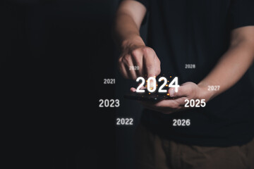 Man Finger pressing on start year 2024 button on smartphone with copy space for text. Concept of...