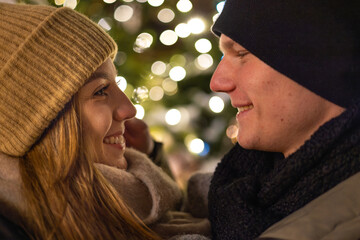 Profile photo of a beautiful young couple in love, enjoying the winter holiday season in the nicely decorated city streets, while celebrating x-mas evening