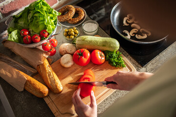 Fresh vegetables on kitchen countertop with woman cooking at home