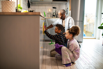 Father and children cleaning home kitchen