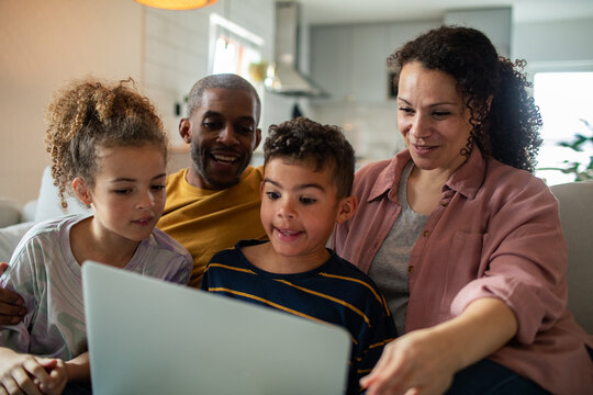 Young family having fun with laptop on couch at home