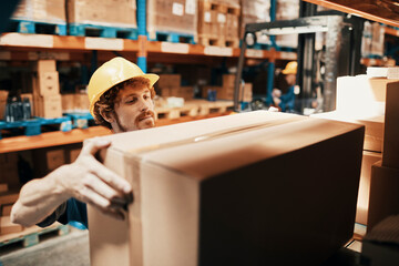 Young man holding box in warehouse
