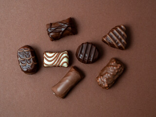 A varied assortment of chocolates arranged on a rich brown background. Chocolate candies close-up.