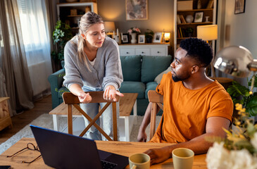 Young mixed couple using a laptop while working on their home finances.