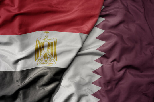 big waving national colorful flag of qatar and national flag of egypt .