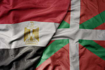 big waving national colorful flag of basque country and national flag of egypt .