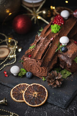 Traditional  French Christmas chocolate dessert  BûchedeNoël (Yule log). Christmas festive pastry in the shape of a log on the dark concrete background