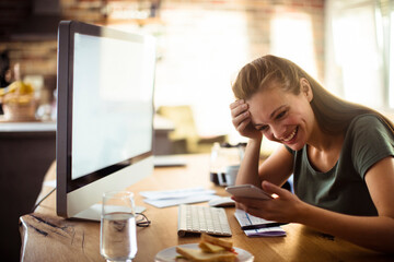 Smiling young woman using smartphone at home office