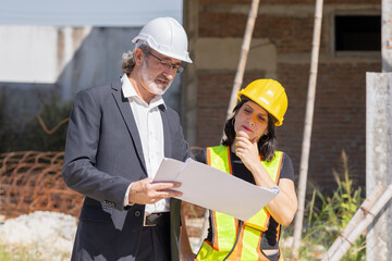 Senior professional architect consulting meeting talking with construction engineer women project manager review planing with floor plan design blueprint.