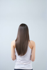 Fototapeta premium The young lady's back, her long silver hair flowing smoothly against the white studio background, showcasing her elegant and chic style. Generative AI.
