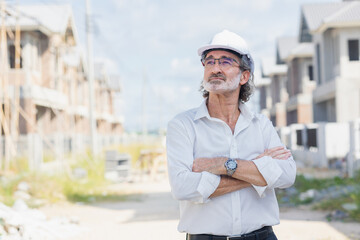 Portrait senior male business man land development investor standing confident in under construction site. Professional real estate project manager man arm folded