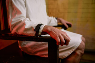 Closeup selective focus on hands of crazy man bound with belt to chair