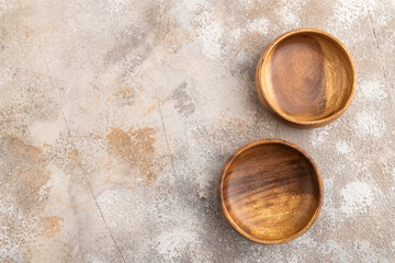 Two empty brown wooden bowl on brown concrete. Top view, copy space
