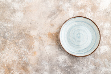 Empty blue ceramic plate on brown concrete background. Top view, copy space