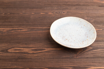 Empty blue and gold ceramic plate on brown wooden. Side view, copy space