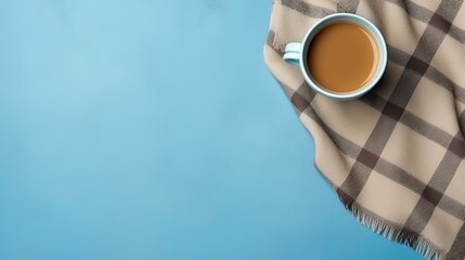 Coffee and warm plaid on a light blue background in a flat lay composition with text space