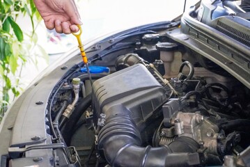 a hand checking the oil level in the engine before a trip or tri