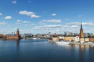panoramic view of rooftops and view of the town hall tower with many colorful houses in stockholm and water channels huge boat and cloudy sky - obrazy, fototapety, plakaty