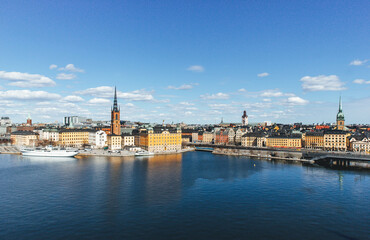 panoramic view of rooftops and view of the town hall tower with many colorful houses in stockholm and water channels huge boat and cloudy sky