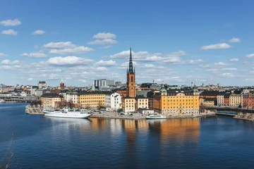 Photo sur Plexiglas Stockholm panoramic view of rooftops and view of the town hall tower with many colorful houses in stockholm and water channels huge boat and cloudy sky