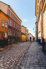 view in morning beautiful light of stone paved street in old town with orange walls in stockholm - obrazy, fototapety, plakaty