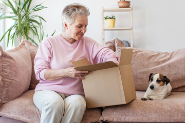 Smiling older adult mature woman customer unpacking parcel