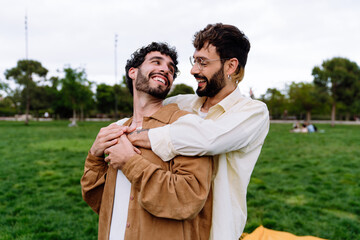 Happy gay couple looking at each other while hugging in park