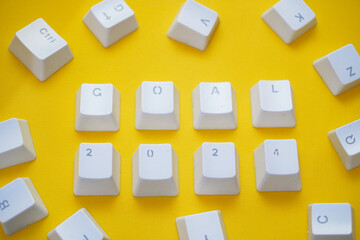 2024 New Year goal, Word GOAL 2024 written on computer keyboard keys isolated on a yellow background.